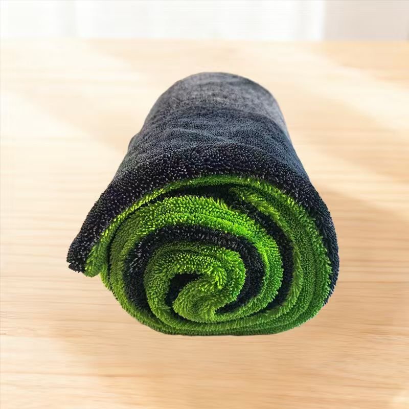 Opgerolde grijs-groene microvezel droogdoek voor de auto op een houten tafel
