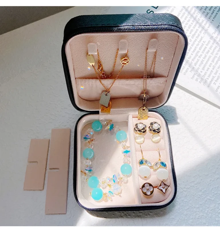 Open zwart leren reissieradendoosje met kettingen, oorbellen en armbanden erin