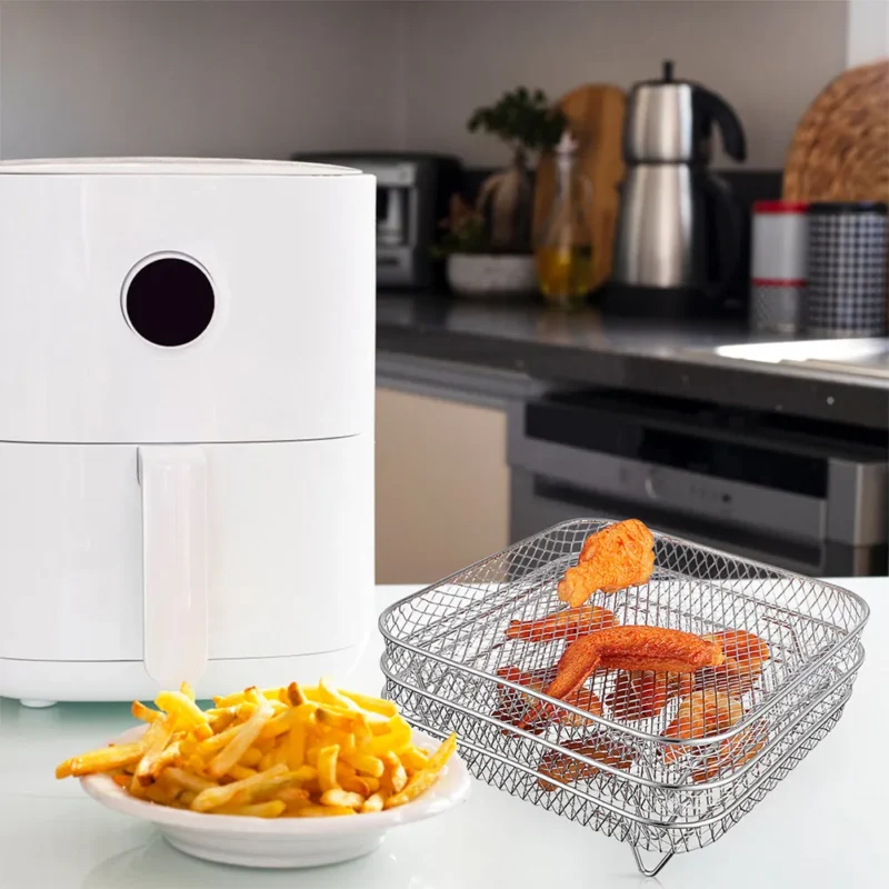 Gestapelde vierkante gaasroosters voor de airfryer met kippenvleugels op een aanrecht
