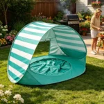 Turquoise-wit gestreepte pop-up strandtent met pierenbadje op een gazon op een zonnige dag