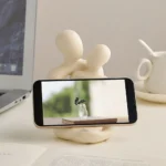 Abstract kunsthars beeldje van een stel op een bureau dat een smartphone vasthoudt, vooraanzicht