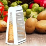 Witte rasp met geraspte kaas in de opvangbak op een houten tafel tussen aardappelen en groenten